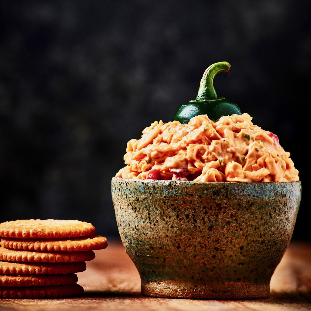 Birdie's Jalapeño pimento cheese in a stone bowl topped with a jalapeño, with crackers